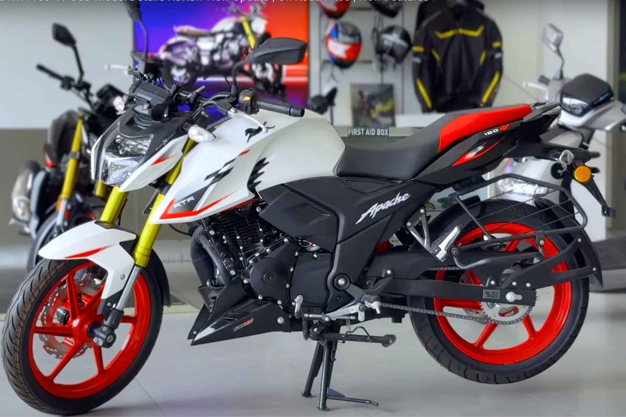 TVS Apache RTR 160 4V बाइक शोरूम में सफेद और लाल रंग की स्टाइलिश स्पोर्ट्स डिज़ाइन के साथ खड़ी हुई है